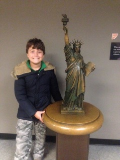 boy with a small bronze statue of Lady Liberty, Liberty Island, New York