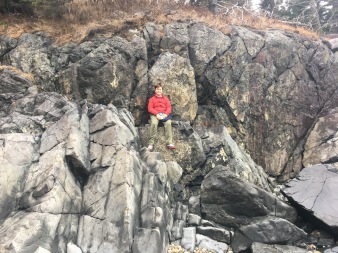 Boy climbing granite rock, Acadia National Park, Maine